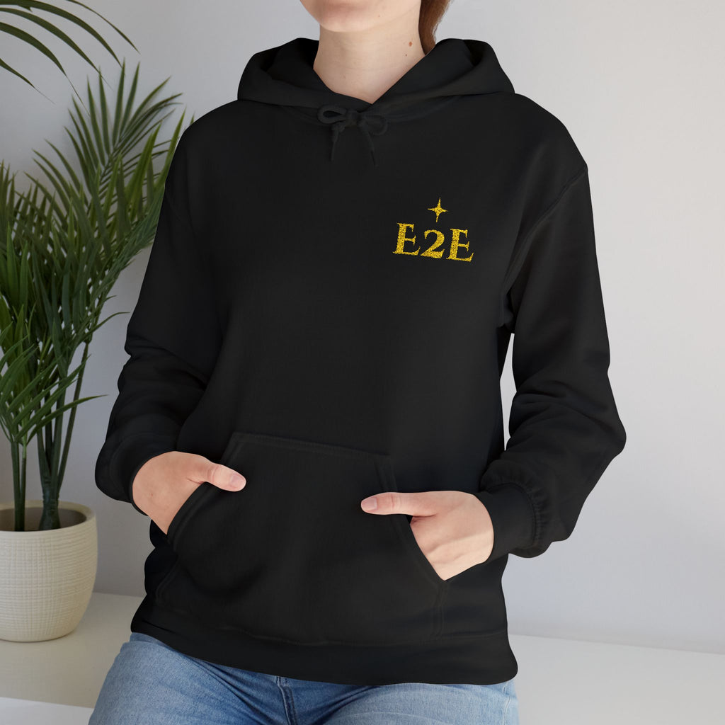 Person wearing a black hoodie with an ‘E2E’ logo on the chest, standing against a neutral background.