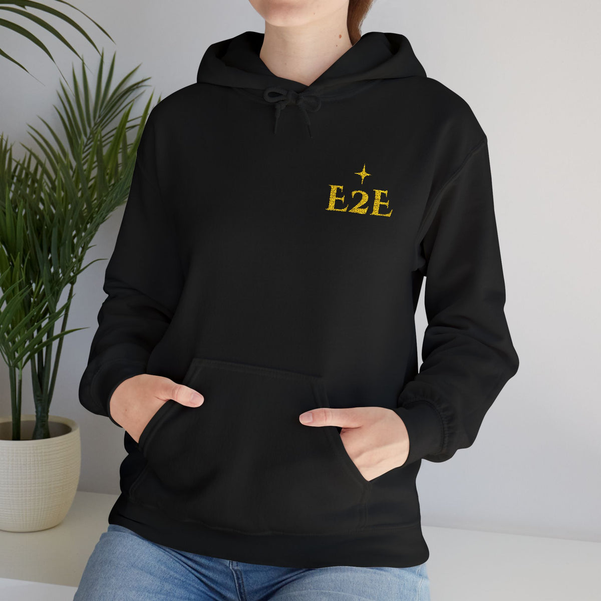 Person wearing a black hoodie with an ‘E2E’ logo on the chest, standing against a neutral background.
