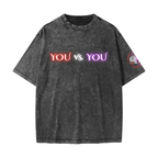 A dark gray mineral-wash t-shirt with a distressed texture, featuring the text 'YOU vs. YOU' printed across the chest in red, white, and purple neon-style lettering, and a circular graphic on the right sleeve.