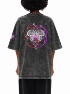 A person shown from the back wearing a faded black graphic t-shirt with a mirrored skull and sacred geometry circle design in purple, red, and white, paired with black pants, against a plain white background.