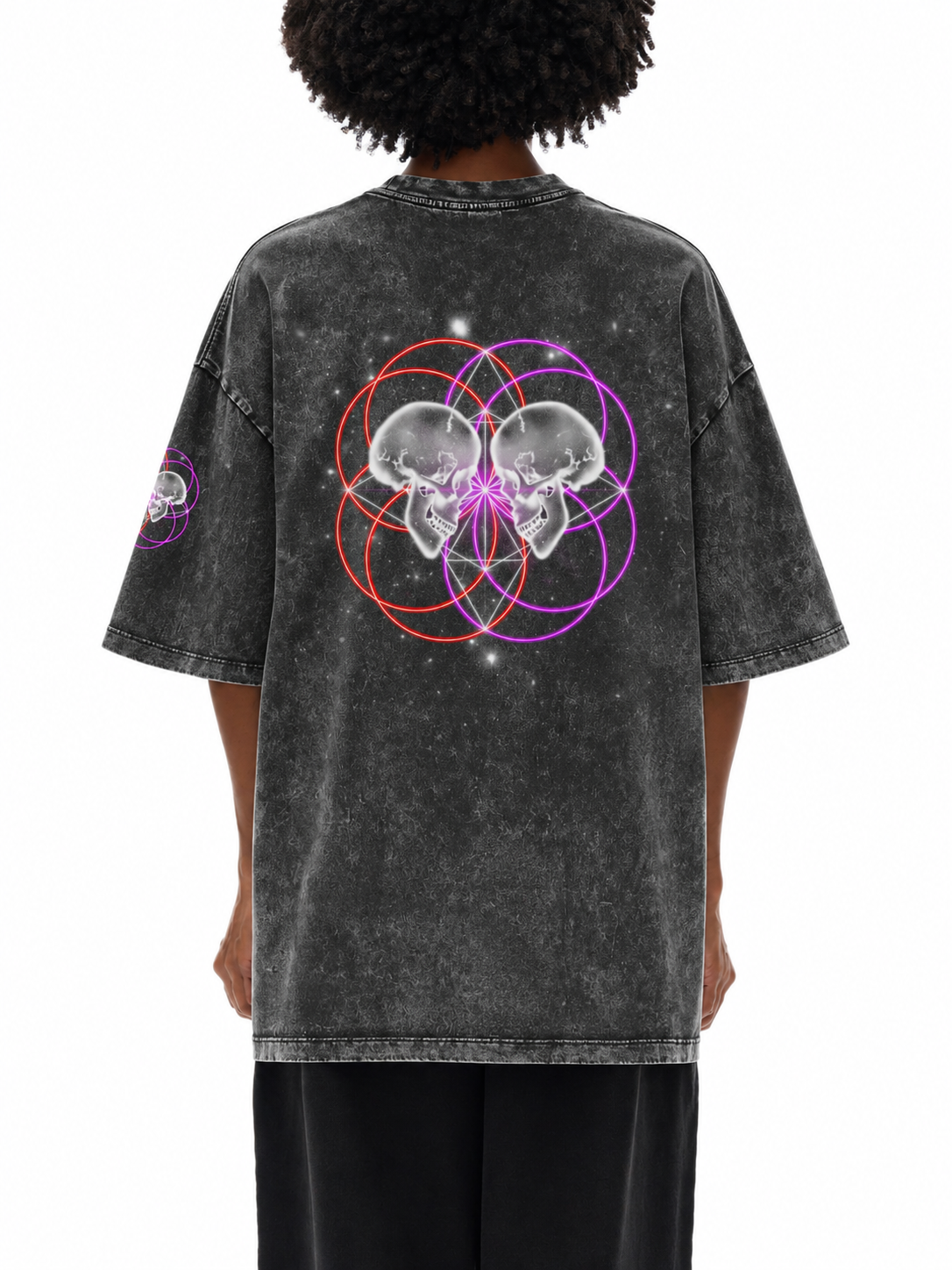 A person shown from the back wearing a faded black graphic t-shirt with a mirrored skull and sacred geometry circle design in purple, red, and white, paired with black pants, against a plain white background.