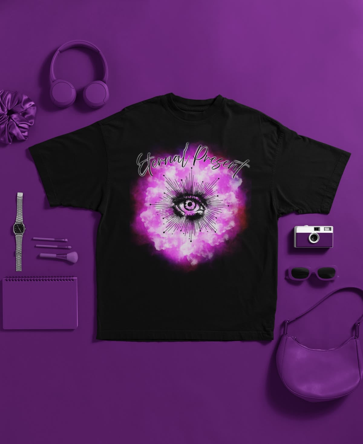 Black t-shirt with a pink and purple design on a purple background, surrounded by accessories.