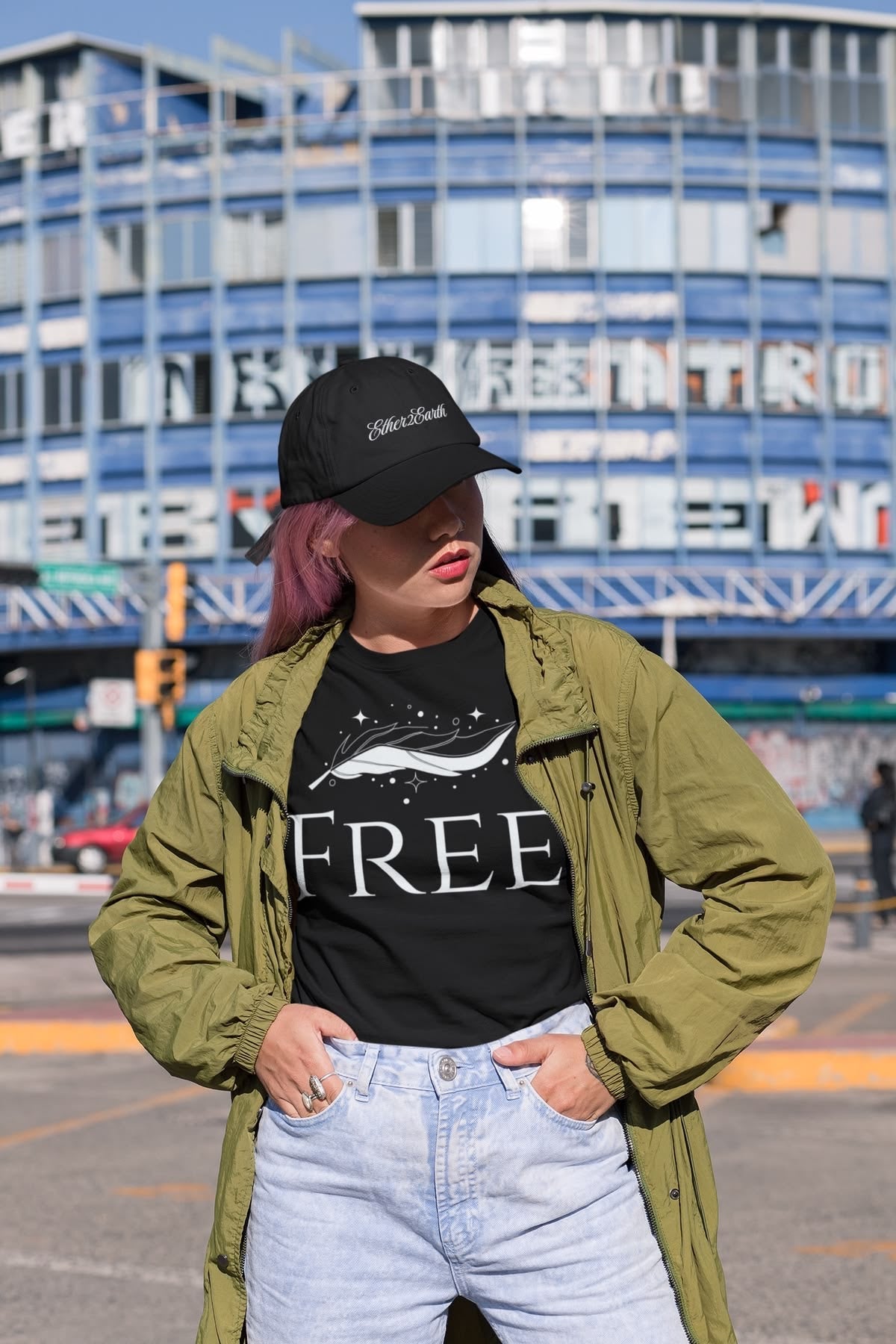 Person wearing a black cap, black t-shirt with a graphic design, and green jacket in an urban setting.